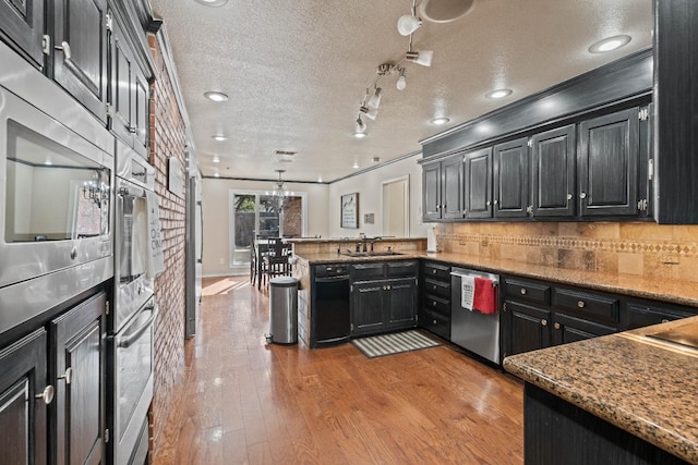 kitchen featuring sink, decorative light fixtures, light wood-type flooring, appliances with stainless steel finishes, and decorative backsplash