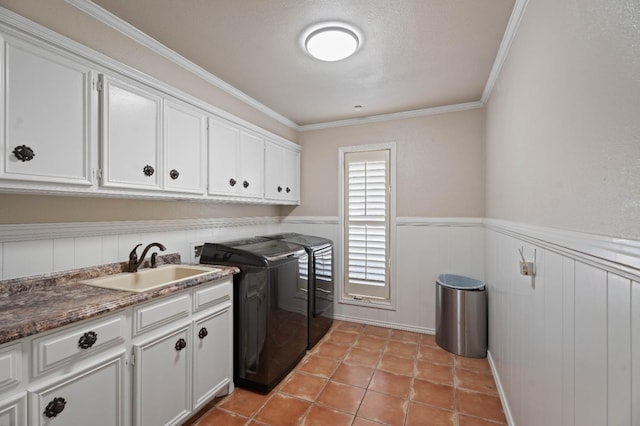 clothes washing area with sink, crown molding, cabinets, light tile patterned floors, and washer and clothes dryer