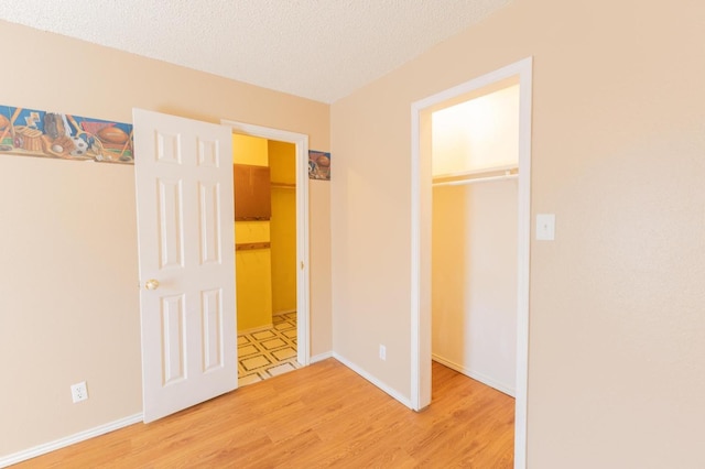 unfurnished bedroom with hardwood / wood-style flooring, a closet, a textured ceiling, and a walk in closet