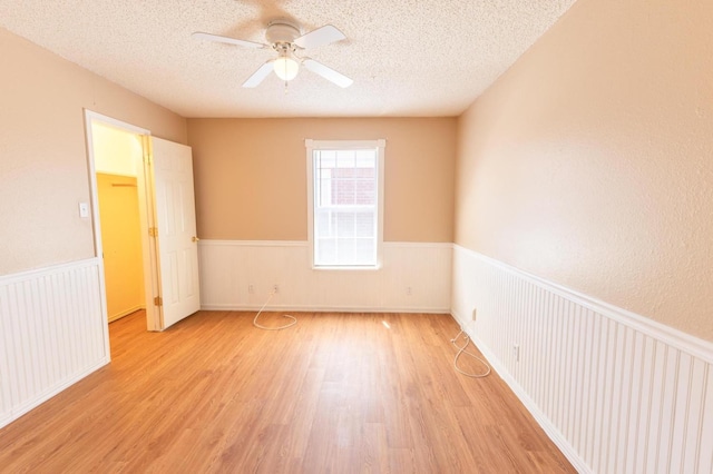 empty room with ceiling fan, a textured ceiling, and light wood-type flooring