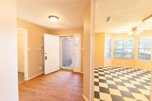 entryway with a textured ceiling, light hardwood / wood-style flooring, and ceiling fan