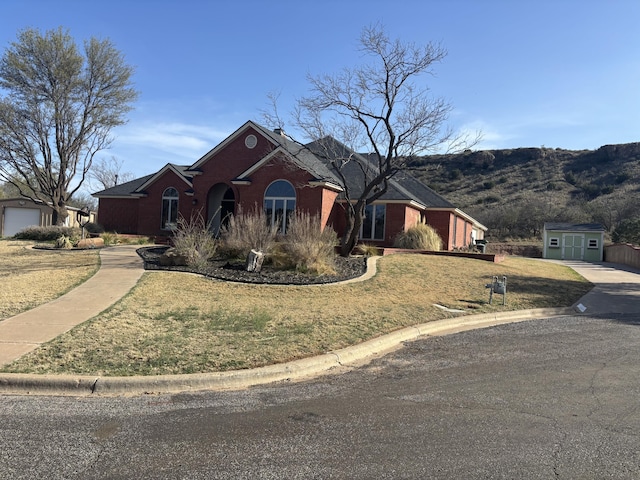 1 Squaw Ln, Ransom Canyon, TX 79366 - view of front of property featuring a front lawn, an outbuilding, a mountain view, and brick siding