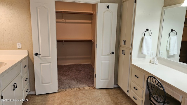 1 Squaw Ln, Ransom Canyon, TX 79366 - full bath with vanity, a walk in closet, a textured wall, and tile patterned flooring