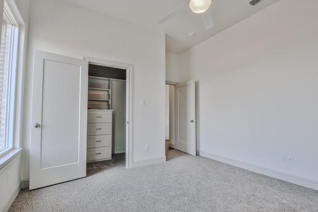 unfurnished bedroom featuring multiple windows, ceiling fan, light carpet, and a closet