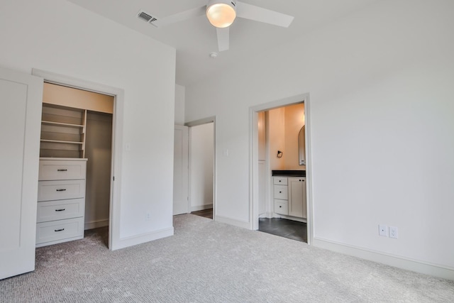 unfurnished bedroom featuring ensuite bath, a spacious closet, carpet flooring, a closet, and ceiling fan