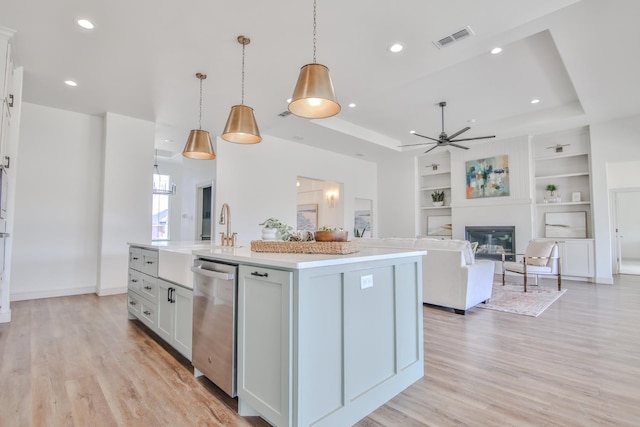 kitchen featuring built in shelves, decorative light fixtures, stainless steel dishwasher, a kitchen island with sink, and white cabinets