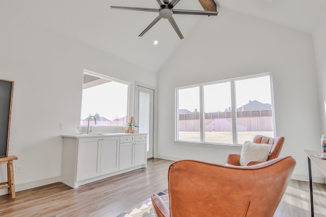 living area featuring sink, high vaulted ceiling, ceiling fan, beam ceiling, and light hardwood / wood-style floors