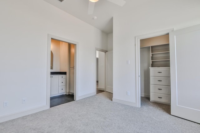 unfurnished bedroom with a walk in closet, light colored carpet, ceiling fan, and a closet