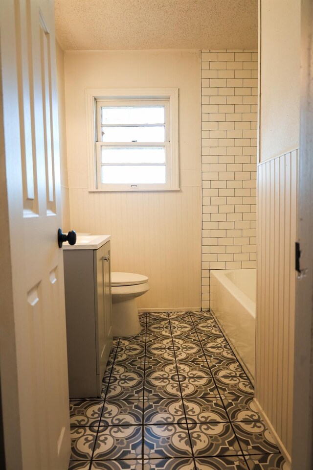 bathroom featuring tile patterned floors, toilet, a textured ceiling, vanity, and a bathing tub