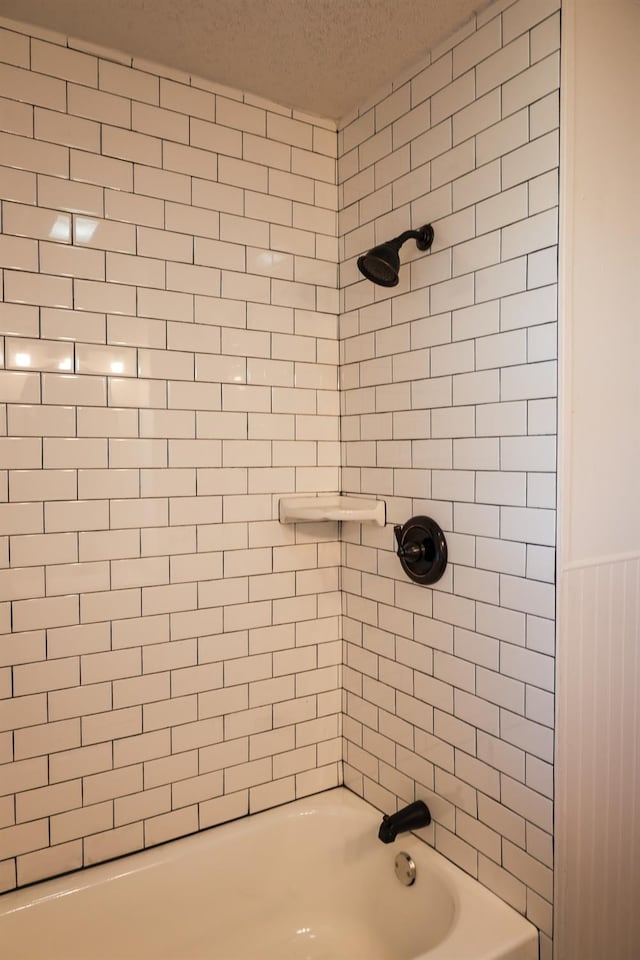 bathroom with tiled shower / bath and a textured ceiling