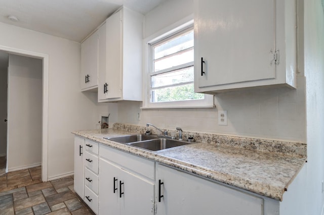 kitchen featuring white cabinetry, sink, and tasteful backsplash