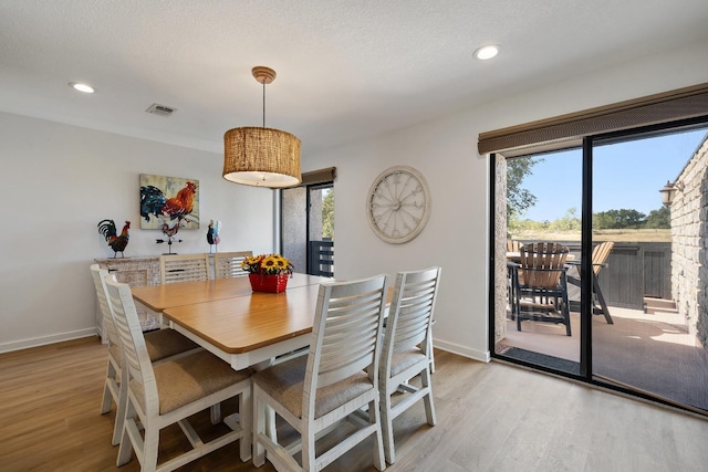 dining room with a textured ceiling and light wood-type flooring