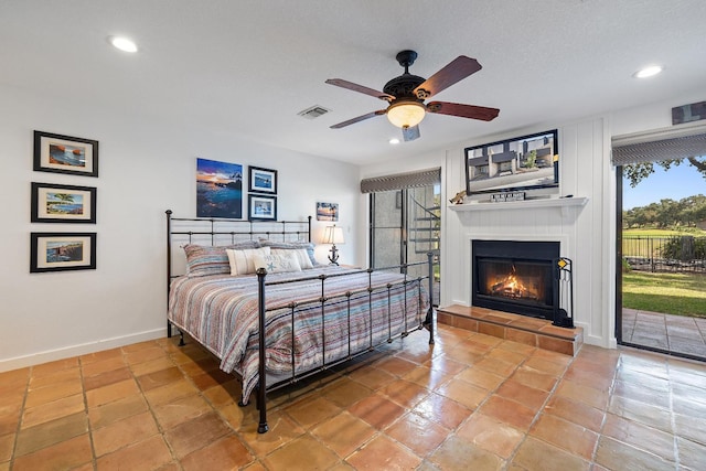 bedroom with ceiling fan, a tile fireplace, multiple windows, and access to outside