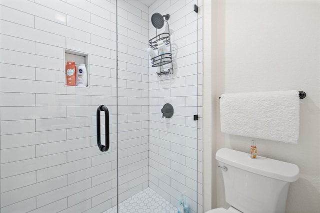 bathroom featuring a shower with door and toilet