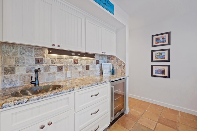 kitchen featuring wine cooler, sink, decorative backsplash, and white cabinets