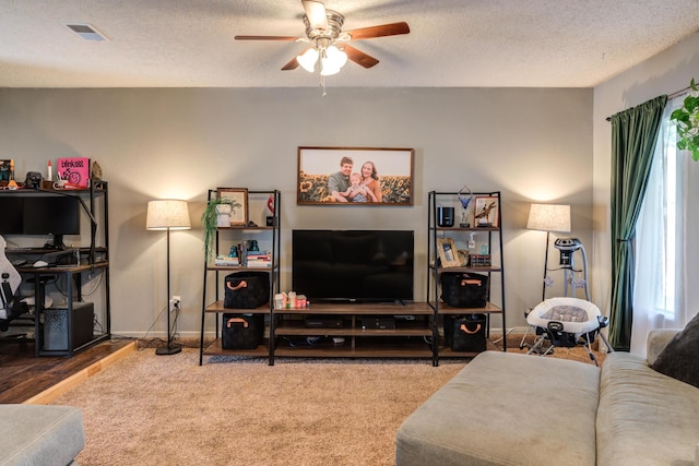 living room featuring visible vents, ceiling fan, a textured ceiling, and carpet