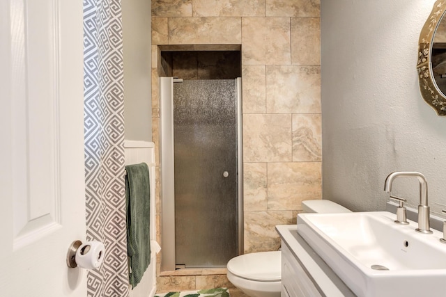 bathroom featuring toilet, a textured wall, a shower stall, and vanity