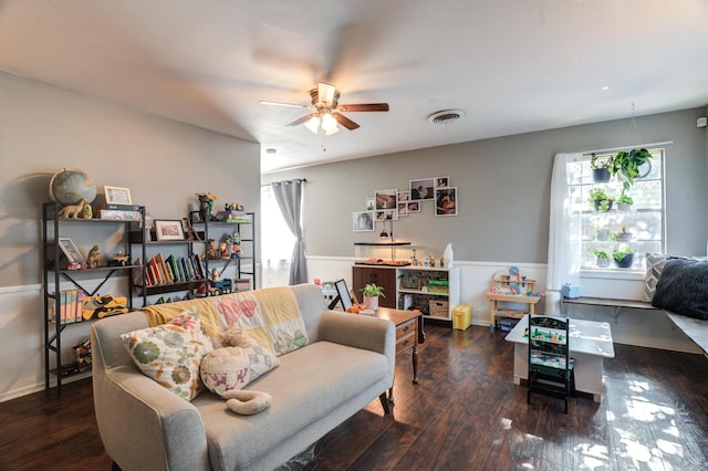 living area featuring a ceiling fan, visible vents, wood finished floors, and a healthy amount of sunlight
