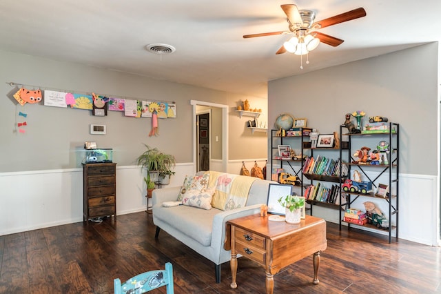 living area featuring visible vents, ceiling fan, wainscoting, and wood finished floors