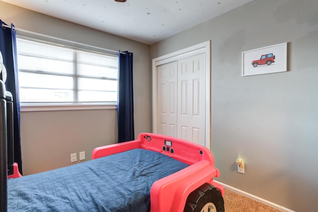 carpeted bedroom featuring a closet and baseboards