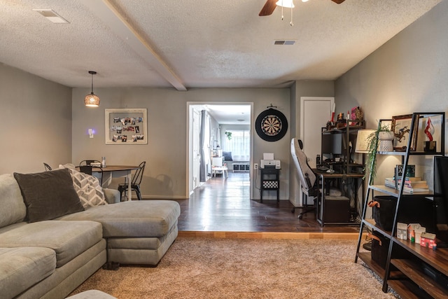 living area with a textured ceiling, visible vents, ceiling fan, and wood finished floors