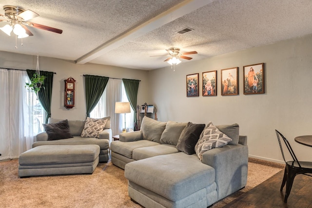 living room featuring a textured ceiling, ceiling fan, visible vents, and baseboards