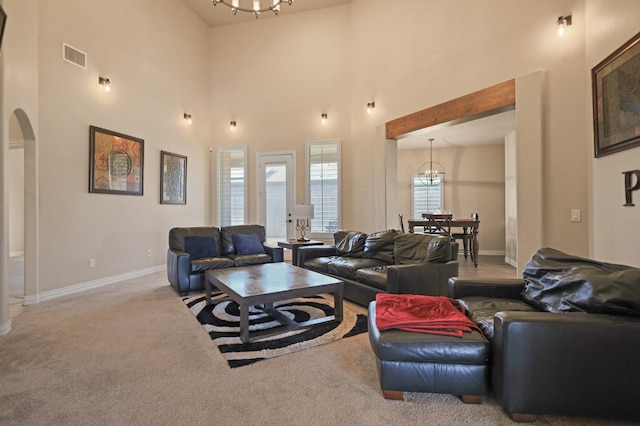 carpeted living room with a chandelier and a high ceiling