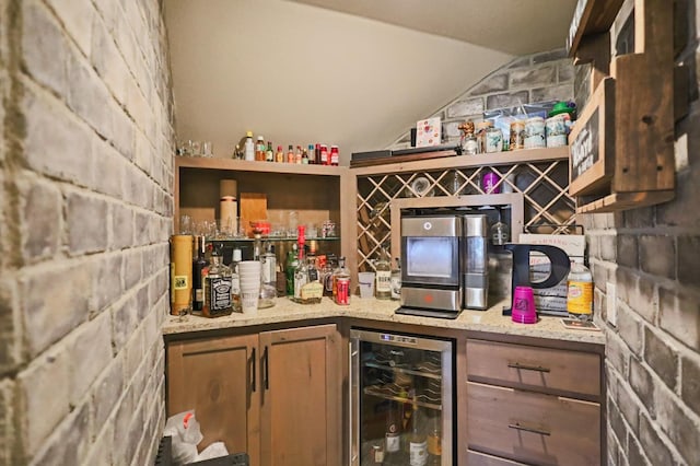 bar with wine cooler, light stone countertops, lofted ceiling, and brick wall