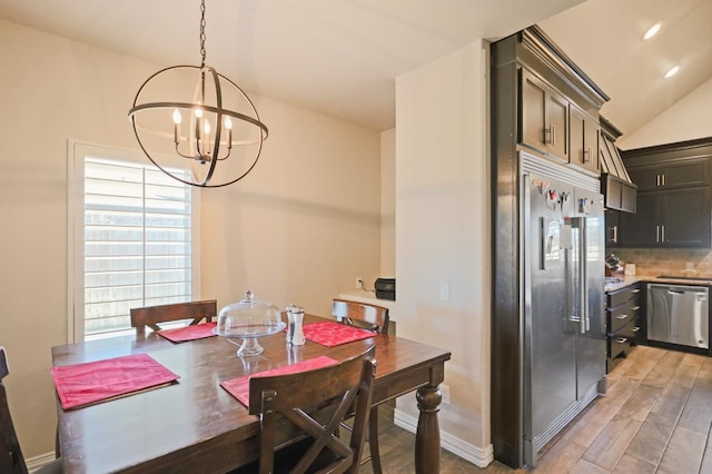 dining space with lofted ceiling, a chandelier, and light wood-type flooring