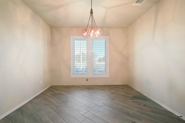 empty room with dark hardwood / wood-style floors and a chandelier