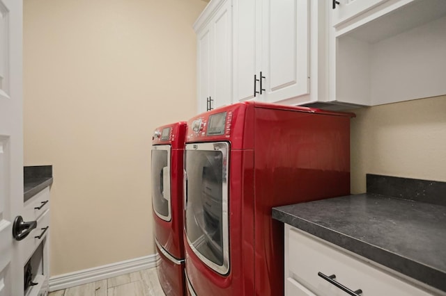 clothes washing area featuring cabinets, washing machine and dryer, and light hardwood / wood-style flooring