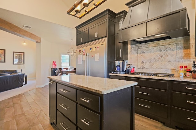 kitchen with appliances with stainless steel finishes, tasteful backsplash, custom exhaust hood, hanging light fixtures, and a center island