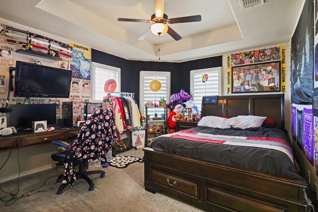 bedroom featuring ceiling fan, a raised ceiling, light carpet, and multiple windows