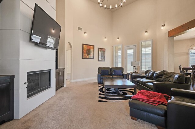 carpeted living room featuring a towering ceiling and a notable chandelier