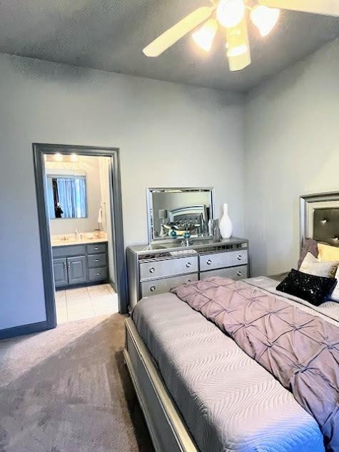 carpeted bedroom featuring sink, ensuite bath, and ceiling fan