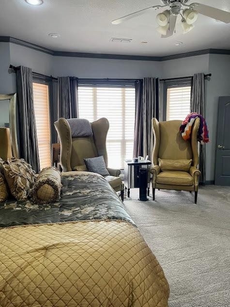 carpeted bedroom featuring multiple windows, ornamental molding, and ceiling fan