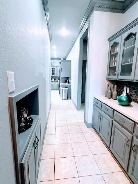 hallway featuring crown molding and light tile patterned floors