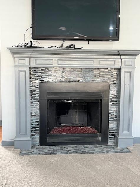 room details with a tiled fireplace and carpet floors