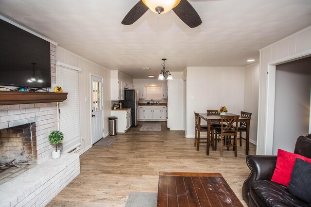 5303 46th St, Lubbock, TX 79414 - living area with light wood-type flooring, ceiling fan with notable chandelier, a fireplace, and visible vents