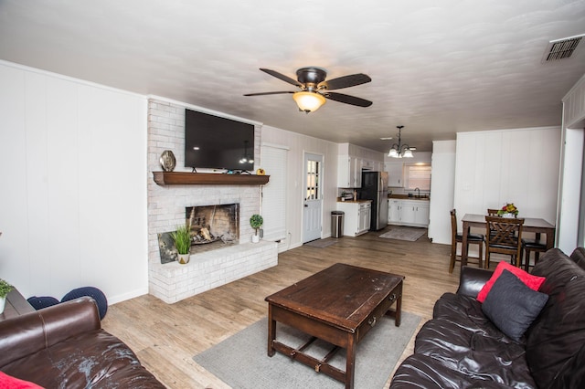 5303 46th St, Lubbock, TX 79414 - living room featuring dark wood-type flooring, ceiling fan with notable chandelier, a fireplace, and visible vents