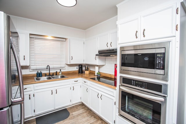 5303 46th St, Lubbock, TX 79414 - kitchen with a sink, ornamental molding, under cabinet range hood, stainless steel appliances, and backsplash