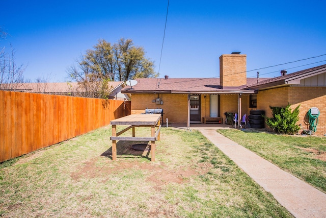 5303 46th St, Lubbock, TX 79414 - rear view of house with a patio area, a yard, a chimney, fence, and brick siding