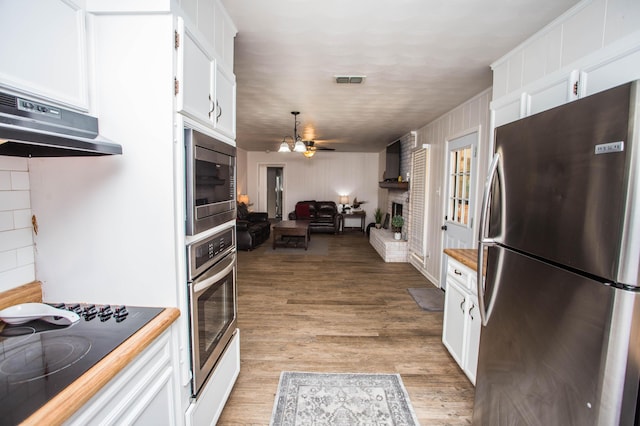 5303 46th St, Lubbock, TX 79414 - kitchen featuring a fireplace, white cabinets, under cabinet range hood, visible vents, and stainless steel appliances