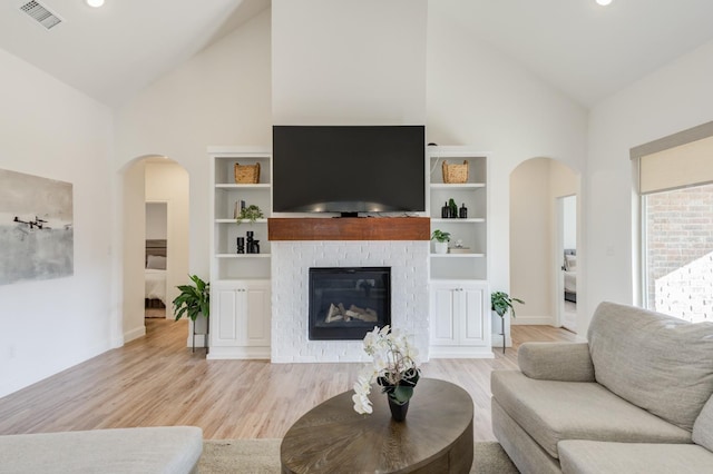 3621 121st St, Lubbock, TX 79423 - living room featuring high vaulted ceiling, arched walkways, light wood-style floors, a fireplace, and recessed lighting