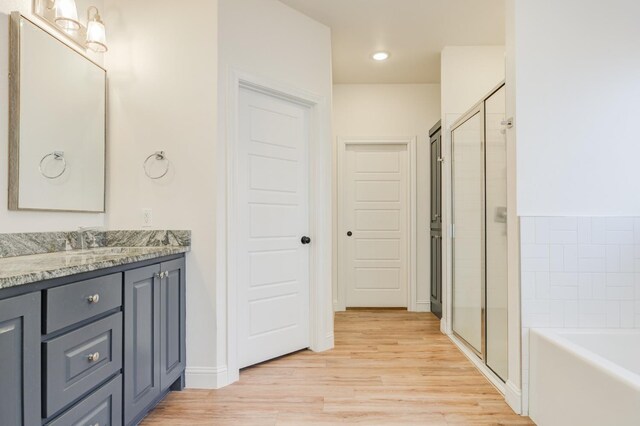 3621 121st St, Lubbock, TX 79423 - bathroom featuring vanity, wood finished floors, a garden tub, a shower stall, and recessed lighting