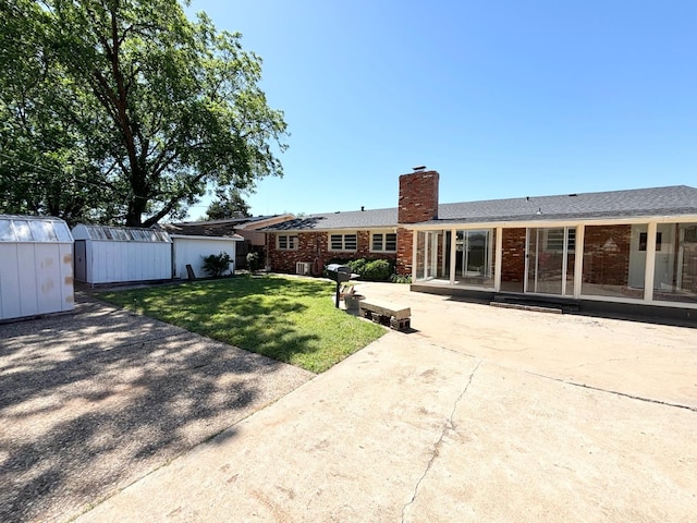 back of house with a storage shed, a yard, and a patio