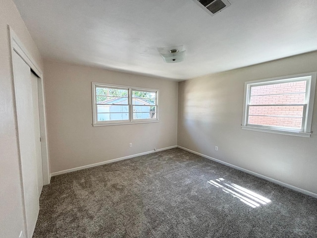 unfurnished bedroom featuring dark carpet and a closet