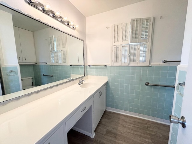 bathroom with hardwood / wood-style flooring, vanity, tile walls, and toilet