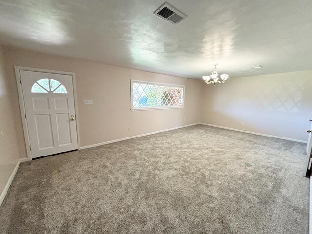 carpeted entrance foyer with an inviting chandelier