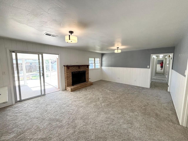 unfurnished living room featuring a brick fireplace, carpet floors, and a textured ceiling